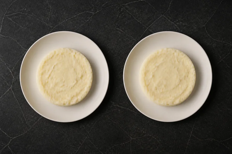 Two plates of mashed potato seen from directly above — the portions look identical.